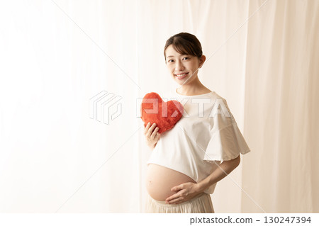 Eight-month pregnant woman holding a red heart Eight-month pregnant woman holding a red heart 130247394