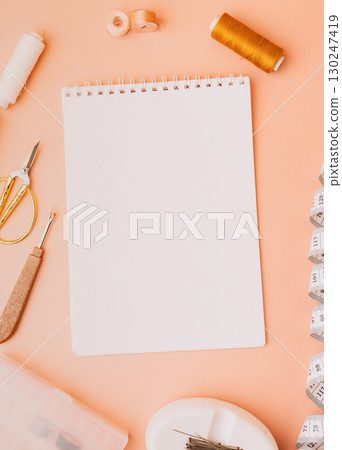 Blank notebook with sewing tools on peach background 130247419