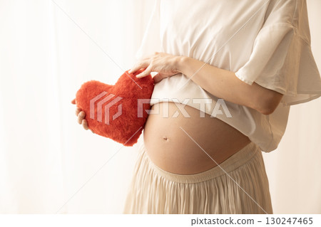 Eight-month pregnant woman holding a red heart Eight-month pregnant woman holding a red heart 130247465