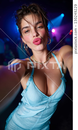 A woman in a blue dress taking a selfie at a nightclub 130249229