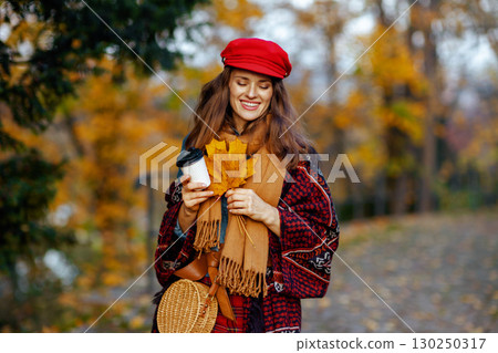 smiling modern woman in red hat with autumn leafs walking smiling modern woman in red hat with autumn leafs walking 130250317