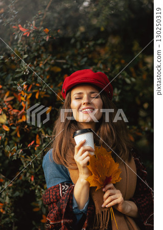 smiling young 40 years old woman in red hat with autumn leafs 130250319
