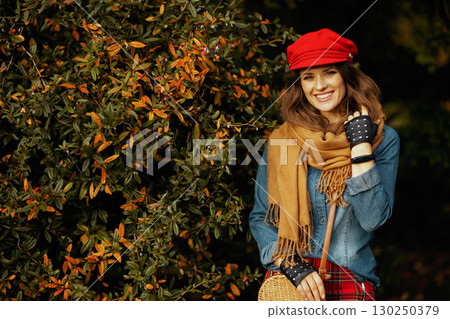Portrait of happy trendy female in jeans shirt and red hat Portrait of happy trendy female in jeans shirt and red hat 130250379