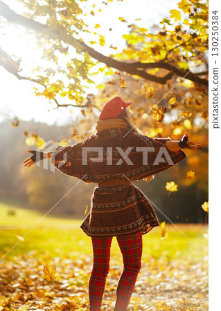 Seen from behind stylish female in red hat with scarf rejoicing 130250384