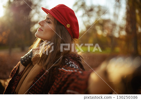 relaxed modern woman in red hat with scarf in city park 130250386