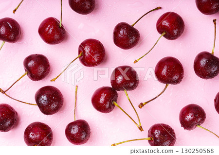 Macro, closeup of wet ripe fresh red cherries with stems, summer fruit on pink background Macro, closeup of wet ripe fresh red cherries with stems, summer fruit on pink background 130250568