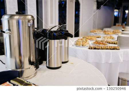 Catering table with hot beverage dispensers and assorted sandwiches for event guests 130250946