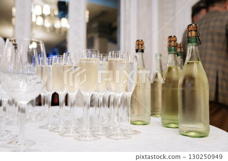 Glasses of chilled sparkling wine and bottles on elegant white table at celebration event 130250949