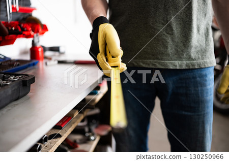 Auto Mechanic Holds A Measuring Tape In The Garage 130250966
