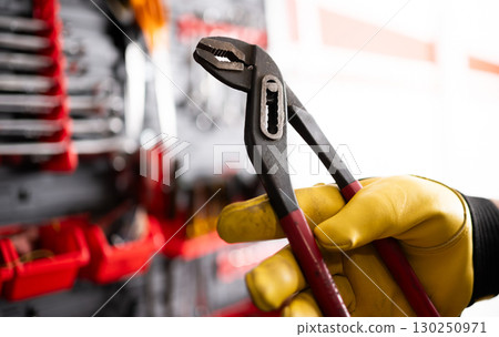 Auto Mechanic With Pliers Against Tool Wall In Service Center Auto Mechanic With Pliers Against Tool Wall In Service Center 130250971