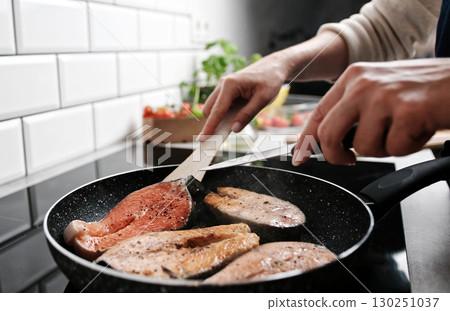 Girl Frying Red Fish Salmon In A Pan On The Kitchen Stove Cooking Healthy Dinner At Home Girl Frying Red Fish Salmon In A Pan On The Kitchen Stove Cooking Healthy Dinner At Home 130251037