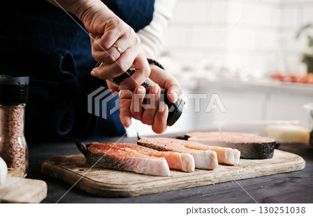 Woman Salting Raw Red Salmon For Cooking Close Up Woman Salting Raw Red Salmon For Cooking Close Up 130251038