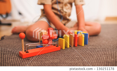 Child playing with colorful wooden toys on a carpet 130251178