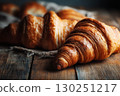 Freshly baked croissants on a rustic wooden table, captured in warm brown tones. 130251217