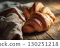Freshly baked croissants on a rustic wooden table, captured in warm brown tones.  130251218