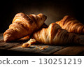 Freshly baked croissants on a rustic wooden surface under dramatic, low-key lighting. 130251219