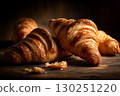 Freshly baked croissants on a rustic wooden surface under dramatic, low-key lighting.  130251220
