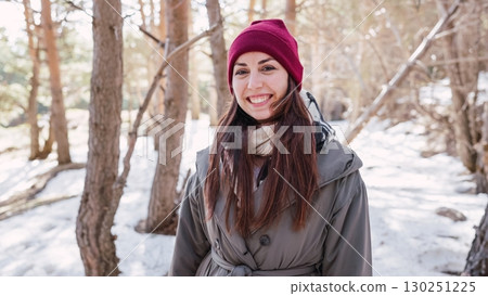 Young woman smiling in snowy forest during winter Young woman smiling in snowy forest during winter 130251225