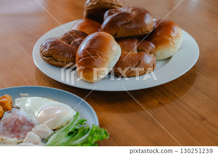 Breakfast consisting of rolls and Japanese and Western side dishes 130251239