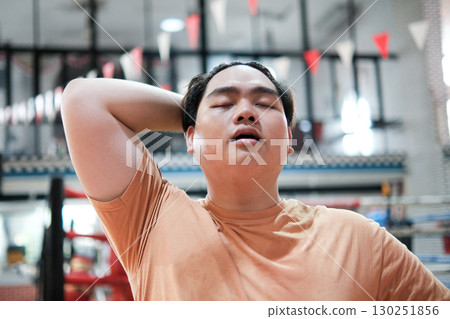 An overweight man is tired and catching his breath after a hard workout in the gym. An overweight man is tired and catching his breath after a hard workout in the gym. 130251856