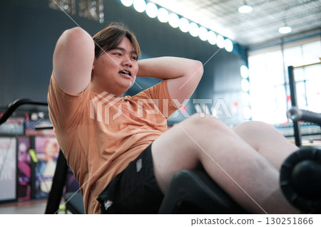 An overweight man is tired and catching his breath after a hard workout in the gym. 130251866