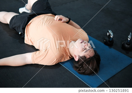 Exhausted man collapsed and lying on the floor after a hard workout. Exhausted man collapsed and lying on the floor after a hard workout. 130251891