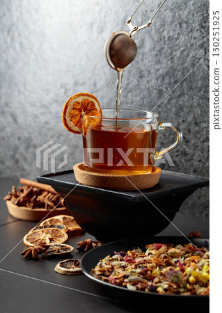 Cup of herbal tea with ingredients and slices of dried orange slices. 130251925