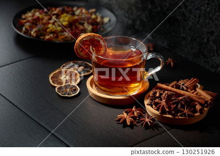 Cup of herbal tea with ingredients and slices of dried orange slices. 130251926