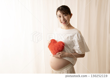 Pregnant woman holding a red heart 130252119