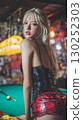 Stylish young woman poses confidently in a vibrant bar setting during the evening 130252303