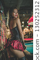 Korean performer in a playful outfit poses confidently in a lively bar with vibrant decor at night 130252312