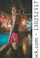 Korean model poses confidently in stylish outfit at vibrant bar during evening hours 130252317