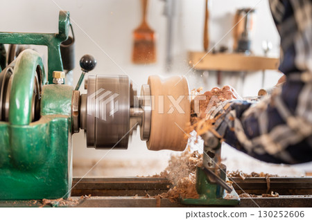 Carpentry. Turnery of a wooden bowl with spiral sawdust shavings with hand and chisel Carpentry. Turnery of a wooden bowl with spiral sawdust shavings with hand and chisel 130252606