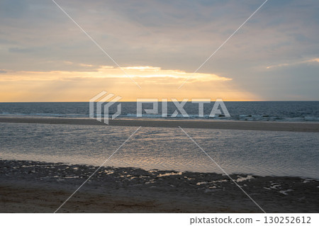 Sunset on the beach near beautiful sea in the evening. Yellow sunlight. Vacation in Ostend, Belgien. Sunset on the beach near beautiful sea in the evening. Yellow sunlight. Vacation in Ostend, Belgien. 130252612