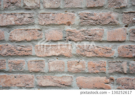 Brown and gray structural stone wall of the ancient building consists of bricks. Nature structural background. 130252617