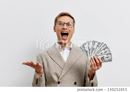 Excited young caucasian man holding fan of dollar bills wear glasses beige jacket isolated on white background smiling success cryptocurrency and Web3 concept Excited young caucasian man holding fan of dollar bills wear glasses beige jacket isolated on white background smiling success cryptocurrency and Web3 concept 130252953