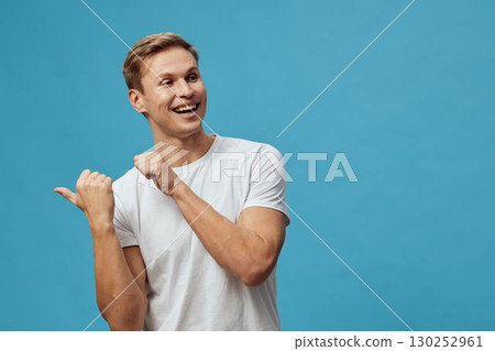 Smiling young man with short hair in casual white t-shirt on a bright blue background, expressing happiness and positivity, cheerful mood, studio portrait, lifestyle concept. 130252961