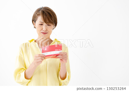 A middle-aged woman looking at her bankbook and worrying 130253264