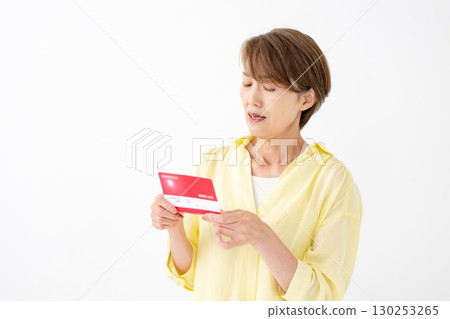A middle-aged woman looking at her bankbook and worrying A middle-aged woman looking at her bankbook and worrying 130253265