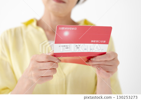 Middle-aged woman looking at her bankbook and worrying 130253273