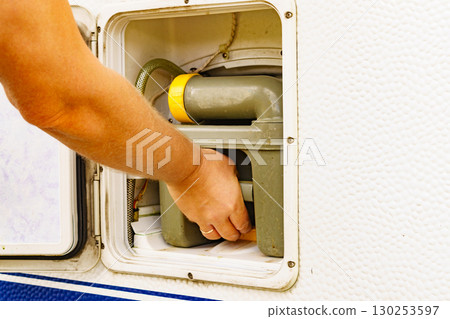 Man serving caravan, tank toilet cassette in dump station. 130253597
