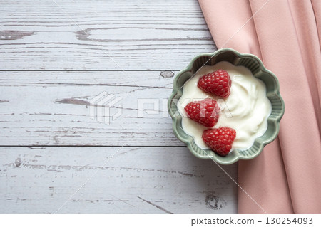 Natural fresh greek yogurt with red raspberry berries in the green plate and napkin for healthy breakfast.  130254093