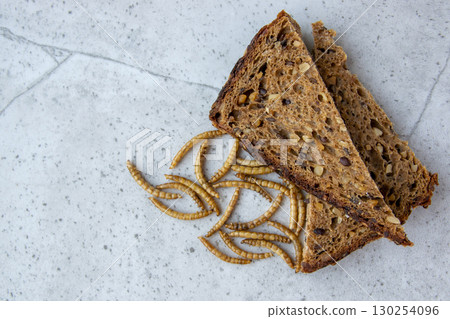 Yellow mealwurm near the bread. Dried worms eating as food or cooked insect meat on the stone background. Good source of protein. Yellow mealwurm near the bread. Dried worms eating as food or cooked insect meat on the stone background. Good source of protein. 130254096