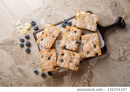 Berry nut blueberry almond sponge cake with powdered sugar close-up on wooden board. horizontal top view 130254107