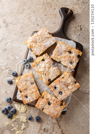 blueberry almond sponge cake with powdered sugar close-up on wooden board. Vertical top view 130254110
