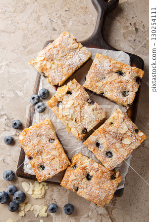 Soft and moist blueberry almond cake closeup on the wooden board. Vertical top view 130254111