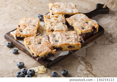 Berry nut blueberry almond sponge cake with powdered sugar close-up on wooden board. horizontal 130254113