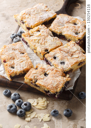 blueberry almond sponge cake with powdered sugar close-up on wooden board. Vertical 130254116