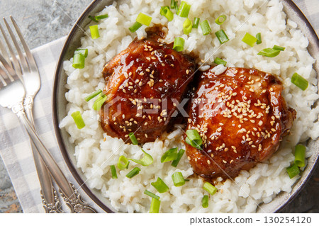 Japanese inspired braised chicken dish made with chicken thighs that simmer in a shoyu based sauce with white rice closeup on the plate. Horizontal top view Japanese inspired braised chicken dish made with chicken thighs that simmer in a shoyu based sauce with white rice closeup on the plate. Horizontal top view 130254120