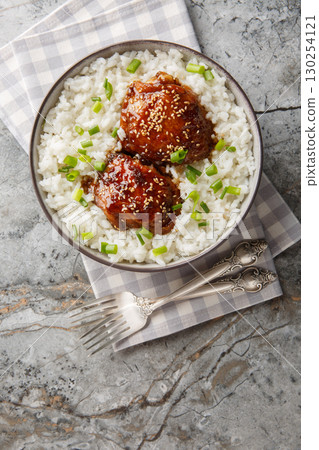 Tasty shoyu chicken is glazed thigh simple soy and brown sugar sauce with white rice closeup on the plate. Vertical top view 130254121